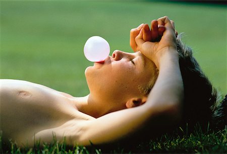 Boy Lying in Field, Blowing Bubble with Bubblegum Stock Photo - Rights-Managed, Code: 700-00018128