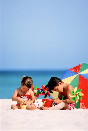 pin wheel family - Enfants en maillot de bain, assis sur la plage avec seau et roulades Photographie de stock - Rights-Managed, Code: 700-00013178