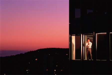simsearch:700-00039942,k - Businessman Standing in Office Tower Window, Using Phone at Dusk Stock Photo - Rights-Managed, Code: 700-00025032