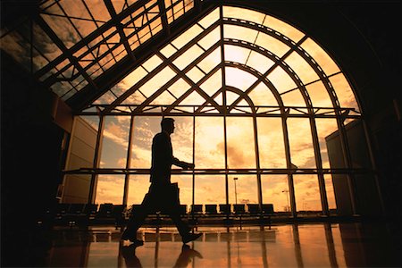 simsearch:700-01345230,k - Silhouette of Businessman Walking Near Window at Sunset Stock Photo - Rights-Managed, Code: 700-00025097