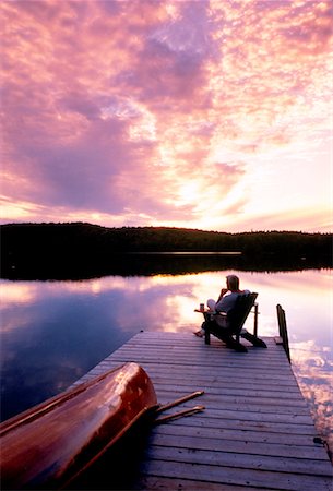 Silhouette of Man Sitting in Chair on Dock at Sunset Fotografie stock - Rights-Managed, Codice: 700-00027423