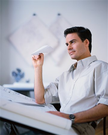 Man Holding Paper Airplane at Drafting Table Stock Photo - Rights-Managed, Code: 700-00034466