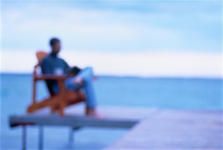 Blurred View of Man Sitting in Chair on Dock Stock Photo - Rights-Managed, Code: 700-00037344
