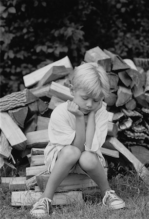 sad boy in black and white - Boy Sitting on Pile of Logs Stock Photo - Rights-Managed, Code: 700-00031462
