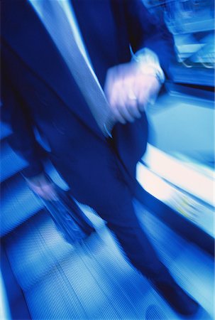 Blurred View of Businessman on Escalator Looking at Watch Stock Photo - Rights-Managed, Code: 700-00045170