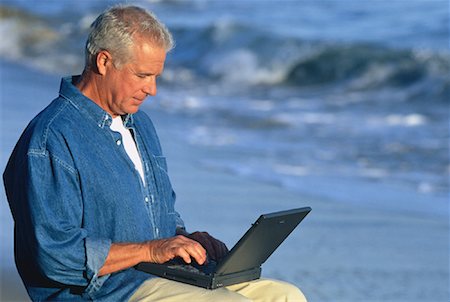 Mature Man Using Laptop Computer On Beach Stock Photo - Rights-Managed, Code: 700-00046884