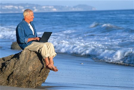Mature Man Using Laptop Computer On Beach Stock Photo - Rights-Managed, Code: 700-00046997