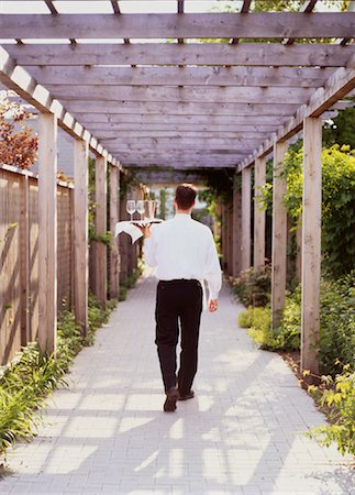 resort service - Back View of Waiter Carrying Tray Through Garden Walkway Stock Photo - Rights-Managed, Code: 700-00047131