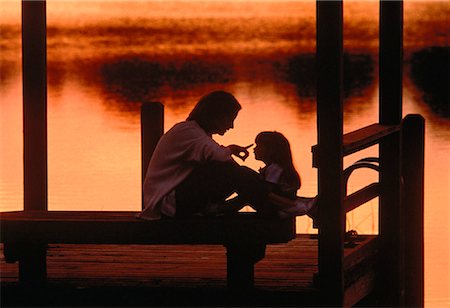 silhouette people sitting on a dock - Mother and Daughter on Dock at Sunset Foto de stock - Con derechos protegidos, Código: 700-00042255
