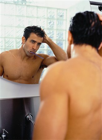 Man Looking at Reflection in Mirror with Toothbrush in Mouth Stock Photo - Rights-Managed, Code: 700-00054189