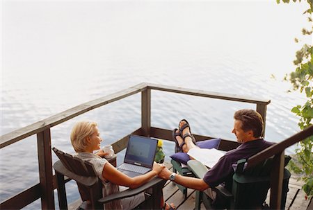 Mature Couple Sitting in Adirondack Chairs on Deck with Laptop Computer Stock Photo - Rights-Managed, Code: 700-00054945