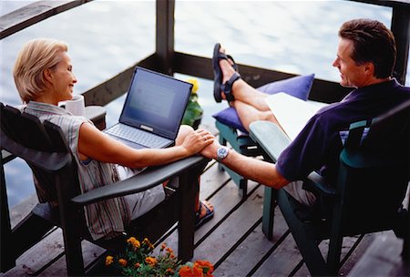 Mature Couple Sitting in Adirondack Chairs on Deck with Laptop Computer Stock Photo - Rights-Managed, Code: 700-00054941