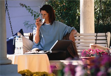Femme assise sur le banc pivotant avec ordinateur portable, l'eau potable Photographie de stock - Rights-Managed, Code: 700-00054958