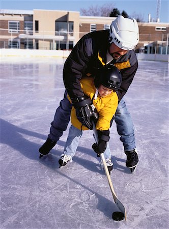 father son hockey - Father Teaching Son to Play Hockey on Outdoor Ice Rink Stock Photo - Rights-Managed, Code: 700-00055378