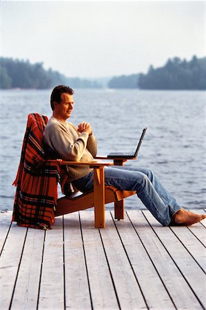 Mature Man Sitting in Adirondack Chair on Dock with Laptop Stock Photo - Rights-Managed, Code: 700-00055663