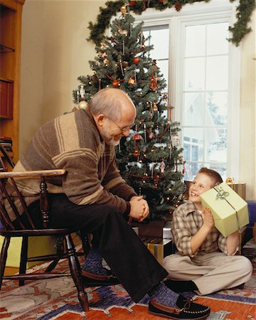 scambio dei regali di natale - Grandfather and Grandson Sitting Near Christmas Tree with Gift Fotografie stock - Rights-Managed, Codice: 700-00057788