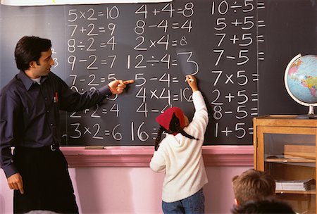 simsearch:632-03516516,k - Male Teacher Watching Girl Write On Blackboard in Classroom Stock Photo - Rights-Managed, Code: 700-00058612