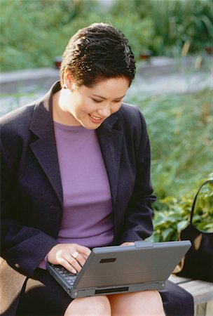 Businesswoman Sitting on Bench Using Laptop Computer Outdoors Stock Photo - Rights-Managed, Code: 700-00051989