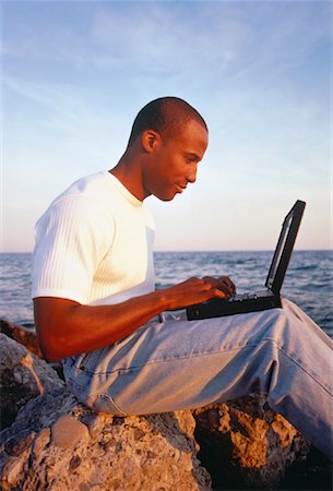 Man Sitting on Rock, Using Laptop Computer near Water Stock Photo - Rights-Managed, Code: 700-00052391