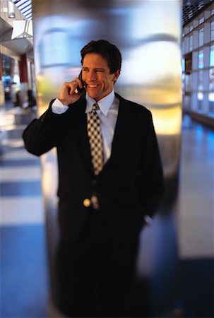 Homme d'affaires, se penchant sur la borne à l'aide de téléphone portable Photographie de stock - Rights-Managed, Code: 700-00053054