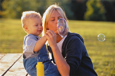 Mother and Son Sitting on Picnic Table Blowing Bubbles Fotografie stock - Rights-Managed, Codice: 700-00053280
