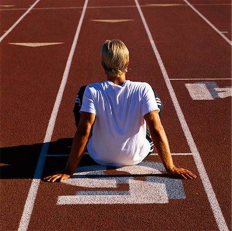 Man Sitting on Starting Line of Running Track Stock Photo - Rights-Managed, Code: 700-00053529