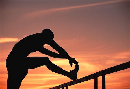 Silhouette of Man Stretching Legs At Sunset Stock Photo - Rights-Managed, Code: 700-00053545