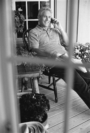 Mature Man Sitting on Porch with Newspaper, Using Cell Phone Stock Photo - Rights-Managed, Code: 700-00053886