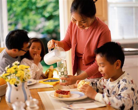 Verre verser du lait de la mère pour fils à la Table du petit déjeuner Photographie de stock - Rights-Managed, Code: 700-00064126