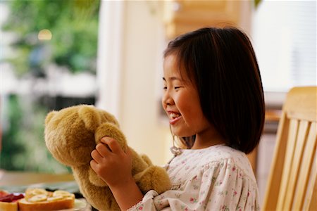 Girl Playing with Plush Toy At Breakfast Table Stock Photo - Rights-Managed, Code: 700-00064122