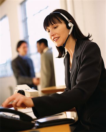 rolodex - Businesswoman Sitting at Desk Using Telephone Headset Foto de stock - Direito Controlado, Número: 700-00064267