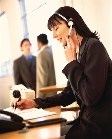 rolodex - Businesswoman Sitting at Desk Using Telephone Headset, Writing Foto de stock - Direito Controlado, Número: 700-00064268