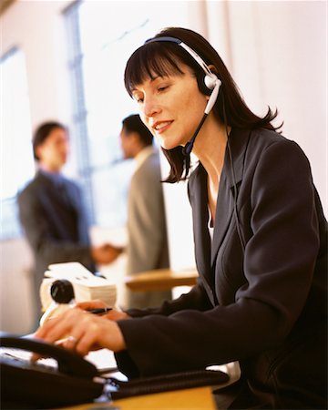 rolodex - Businesswoman Sitting at Desk Using Telephone Headset Foto de stock - Direito Controlado, Número: 700-00064270