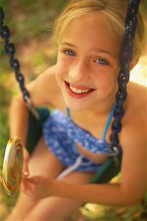 Portrait de jeune fille, assis sur une balançoire tenant Lollipop Photographie de stock - Rights-Managed, Code: 700-00066160