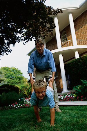 father child yard not illustration not business not vintage not 20s not 30s not 40s not 70s not 80s - Father Holding Son's Legs as Wheelbarrow Outdoors Stock Photo - Rights-Managed, Code: 700-00067017