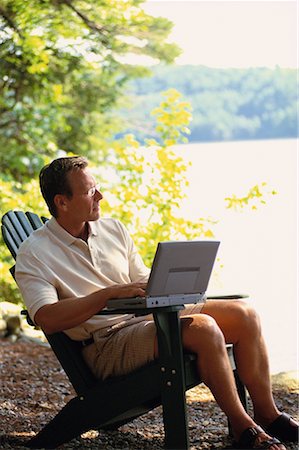 Man Sitting in Chair with Laptop Computer near Lake Stock Photo - Rights-Managed, Code: 700-00067090