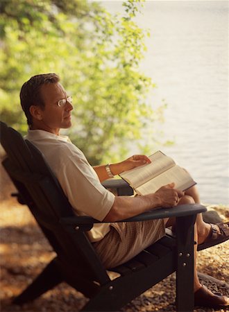 Man Sitting in Chair with Book Near Lake Stock Photo - Rights-Managed, Code: 700-00067111