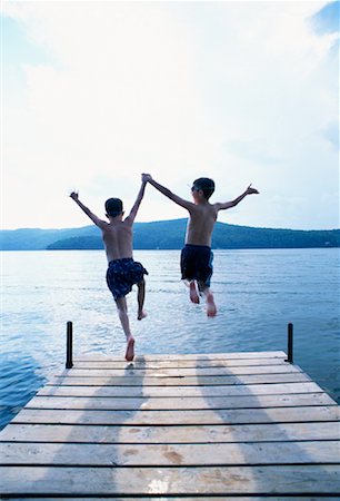 Vue arrière du garçons en maillot de bain sautant dans l'eau du quai Photographie de stock - Rights-Managed, Code: 700-00067744