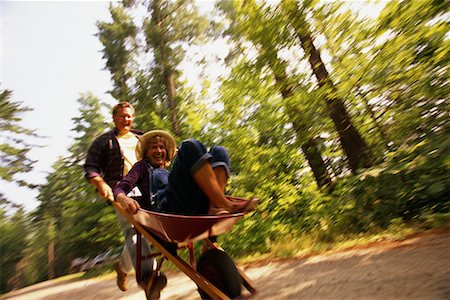 Mature Man Pushing Mature Woman In Wheelbarrow Outdoors Stock Photo - Rights-Managed, Code: 700-00068248