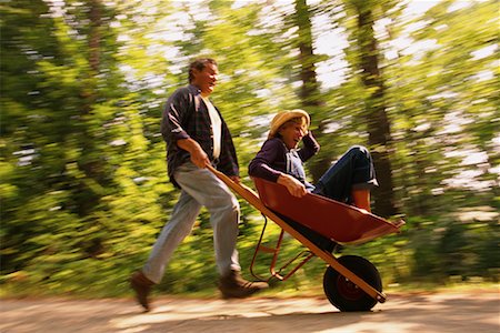 Mature Man Pushing Mature Woman In Wheelbarrow Outdoors Stock Photo - Rights-Managed, Code: 700-00068249