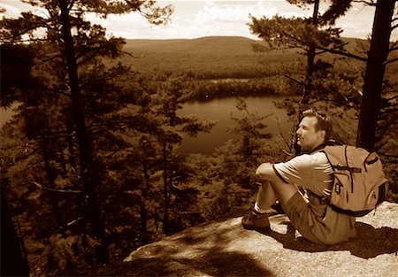 Homme assis sur les rochers, surplombant le paysage Photographie de stock - Rights-Managed, Code: 700-00068621