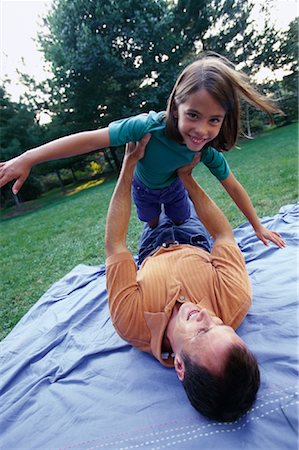 father child yard not illustration not business not vintage not 20s not 30s not 40s not 70s not 80s - Father Lying in Field, Holding Daughter in Air Stock Photo - Rights-Managed, Code: 700-00069468