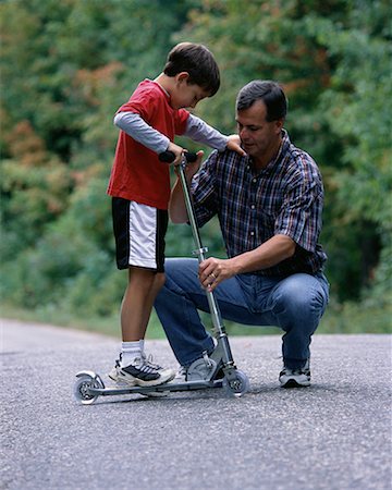 sports scooters - Father Helping Son Ride Scooter Outdoors, Ontario, Canada Foto de stock - Con derechos protegidos, Código: 700-00069530