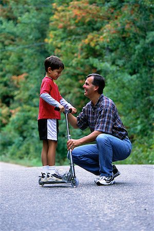 sports scooters - Father Helping Son Ride Scooter Outdoors, Ontario, Canada Foto de stock - Con derechos protegidos, Código: 700-00069531