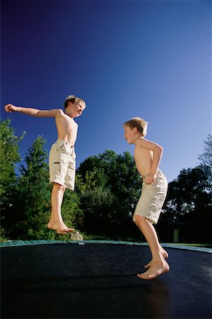 Twin Boys Jumping on Trampoline Outdoors Stock Photo - Rights-Managed, Code: 700-00069555
