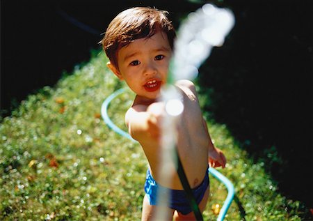 Portrait of Boy in Swimwear Holding Water Hose Outdoors Stock Photo - Rights-Managed, Code: 700-00060110