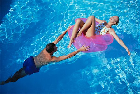 swimming pool push - Homme poussant femme dans un fauteuil gonflable piscine Photographie de stock - Rights-Managed, Code: 700-00061852
