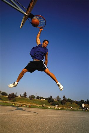 Man Jumping in Air to Slam Dunk Basketball Stock Photo - Rights-Managed, Code: 700-00062521