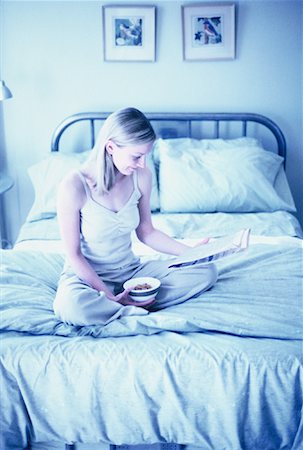 simsearch:700-00062758,k - Woman Sitting on Bed Reading Newspaper, Holding Bowl of Cereal Stock Photo - Rights-Managed, Code: 700-00062759