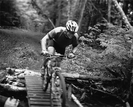 Man Riding Mountain Bike over Wooden Walkway through Forest Stock Photo - Rights-Managed, Code: 700-00062893